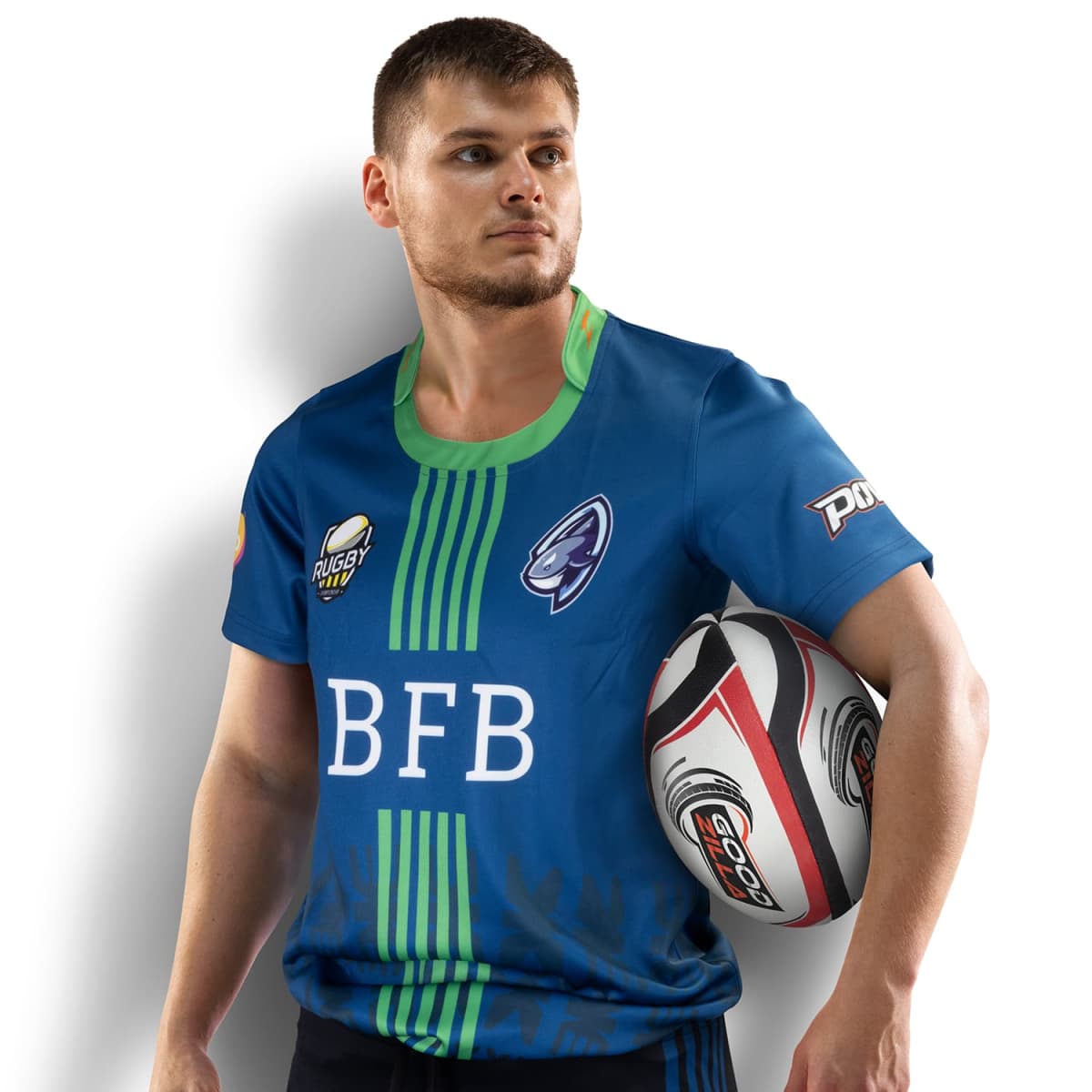 A man in a blue and green rugby jersey holds a rugby ball under his left arm. He gazes to his right, standing against a white background. Logos on the jersey include BFB and other rugby-related designs.