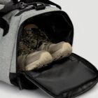 A pair of hiking boots stored inside a gray duffel bag with an open zippered compartment.