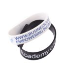 White and black wristbands with text promoting a business and academy.