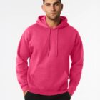 Man wearing a bright pink hoodie and black pants, standing against a plain white background.