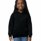 Smiling girl with braided hair wears a black hoodie and blue jeans against a white background.