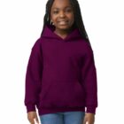 Smiling girl in a purple hoodie and jeans standing against a white background.