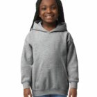 Smiling girl in a gray hoodie and jeans, standing against a plain white background.