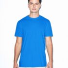 A person stands against a white background wearing a bright blue T-shirt and light gray pants. They have short dark hair and are looking directly at the camera with a neutral expression.