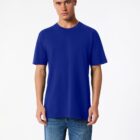 Person wearing a plain blue T-shirt and blue jeans stands against a plain white background.