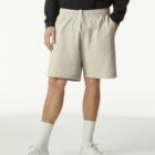 Person wearing beige shorts, white socks, white sneakers, and a black sweatshirt.