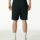 A person wearing black shorts, white socks, and black shoes, shown from the back.