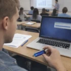 Student using a laptop in class holds a 3.0 Promotional Usb.