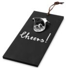 Black bottle opener plaque with cheers! written on it, featuring a metal opener and a loop.