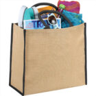 Canvas tote filled with shoes, a magazine, sunglasses, a water bottle, and a colorful scarf.
