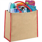 Beige tote bag with red handles, filled with magazines, shoes, sunglasses, and a water bottle.