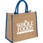 A Whole Foods Market jute tote bag with blue handles and trim.