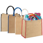 Three jute tote bags with black, blue, and red handles, filled with various colorful items.