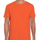 A person wearing an orange t-shirt and dark pants stands against a plain white background, smiling.
