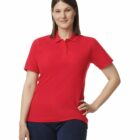 Woman in a red polo shirt and dark jeans standing with one hand on her hip, smiling.