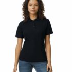 Woman with curly hair wearing a black polo shirt and blue jeans, standing and facing forward.