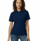 Woman wearing a navy blue polo shirt and jeans, standing against a white background.
