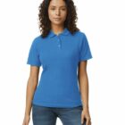 Woman wearing a blue polo shirt and jeans standing against a white background.