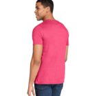 A man wearing a pink T-shirt and blue jeans is standing with his back to the camera, looking over his shoulder and smiling. The background is plain white.