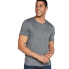 Man wearing a gray t-shirt and blue jeans, standing and smiling against a white background.