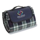 Folded tartan picnic blanket with a black flap and Mecanex logo.