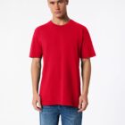 A person wearing a plain red T-shirt and blue jeans stands against a white background. They have short hair and a neutral expression, with their hands relaxed by their sides.