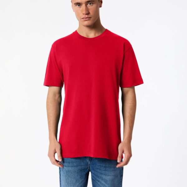 A person wearing a plain red T-shirt and blue jeans stands against a white background. They have short hair and a neutral expression, with their hands relaxed by their sides.