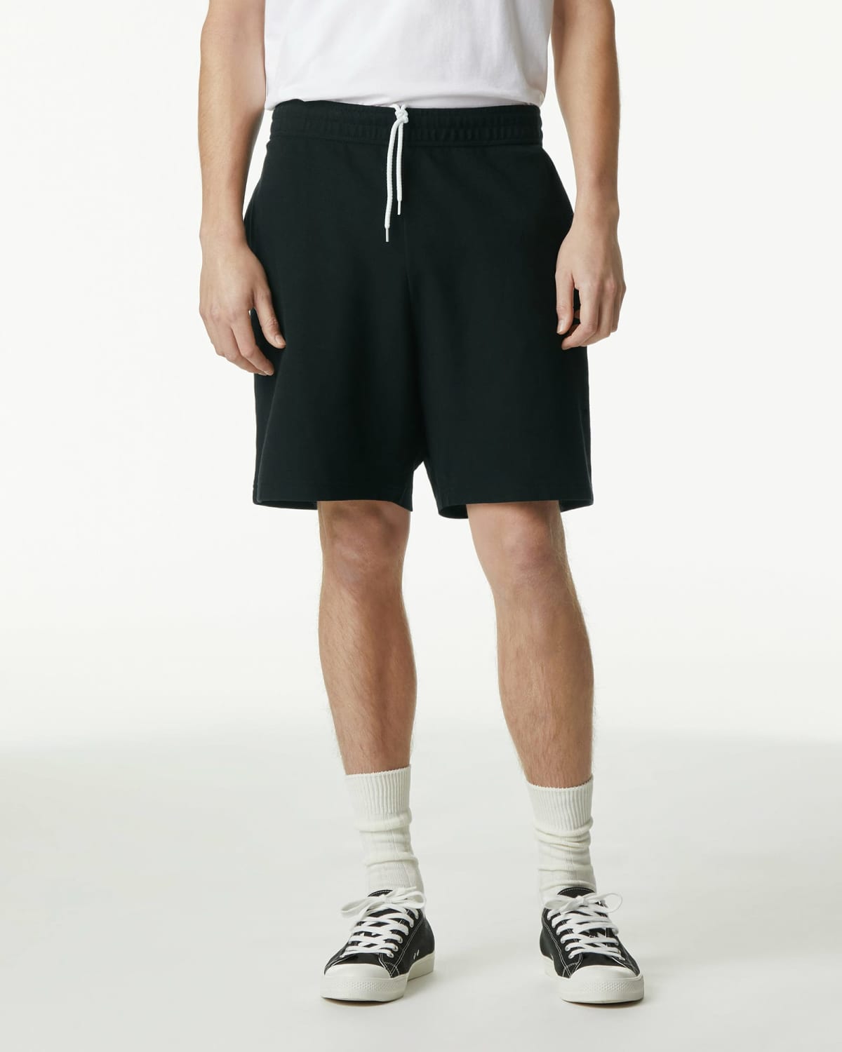 Person wearing black shorts, a white t-shirt, socks, and black sneakers, standing upright.