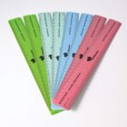 A set of six translucent plastic rulers in green, blue, and red, fanned out on a white surface. Each ruler has measurement markings and the text Discover. Learn. Preserve. along with a logo in black.