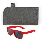 Red sunglasses with dark lenses are placed in front of a gray felt case. The case has a small black tag indicating it is made from recycled plastic bottles.