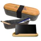 A bamboo and felt pencil case with a ruler on top, containing a pen and pencil. The lid doubles as a phone stand. A phone is placed on the stand nearby.