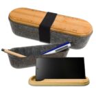 A felt pencil case with a wooden lid featuring a ruler design is shown open with pens inside. The lid also serves as a phone stand, holding a smartphone upright.