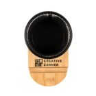 Black round cup on a wooden holder labeled Creative Corner, viewed from above.