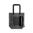 Gray tote bag with a pen, notebook, black bottle, and bag of colorful candy.