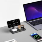 Desk with charging station holding a smartphone, smartwatch, wireless earbuds, and a laptop nearby.