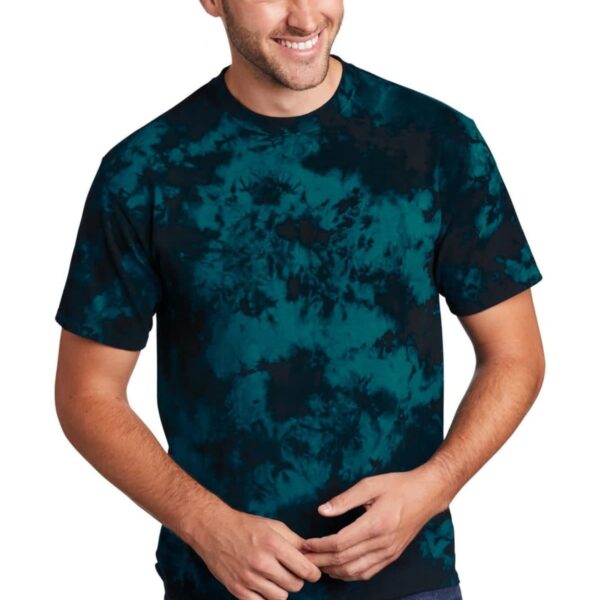 Man wearing a blue and black tie-dye shirt, smiling with hands clasped.