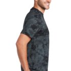 Man in tie-dye shirt and jeans smiling in side profile view.