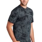 Man in a black tie-dye t-shirt and jeans standing against a white background.