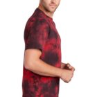 Man in red and black tie-dye shirt and jeans, looking sideways.
