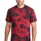 Man wearing a red and black tie-dye t-shirt with blue jeans.
