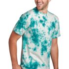 Man in a blue tie-dye T-shirt and jeans, smiling and looking to the side.