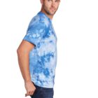 Man in blue tie-dye shirt and jeans standing sideways, looking to the left.