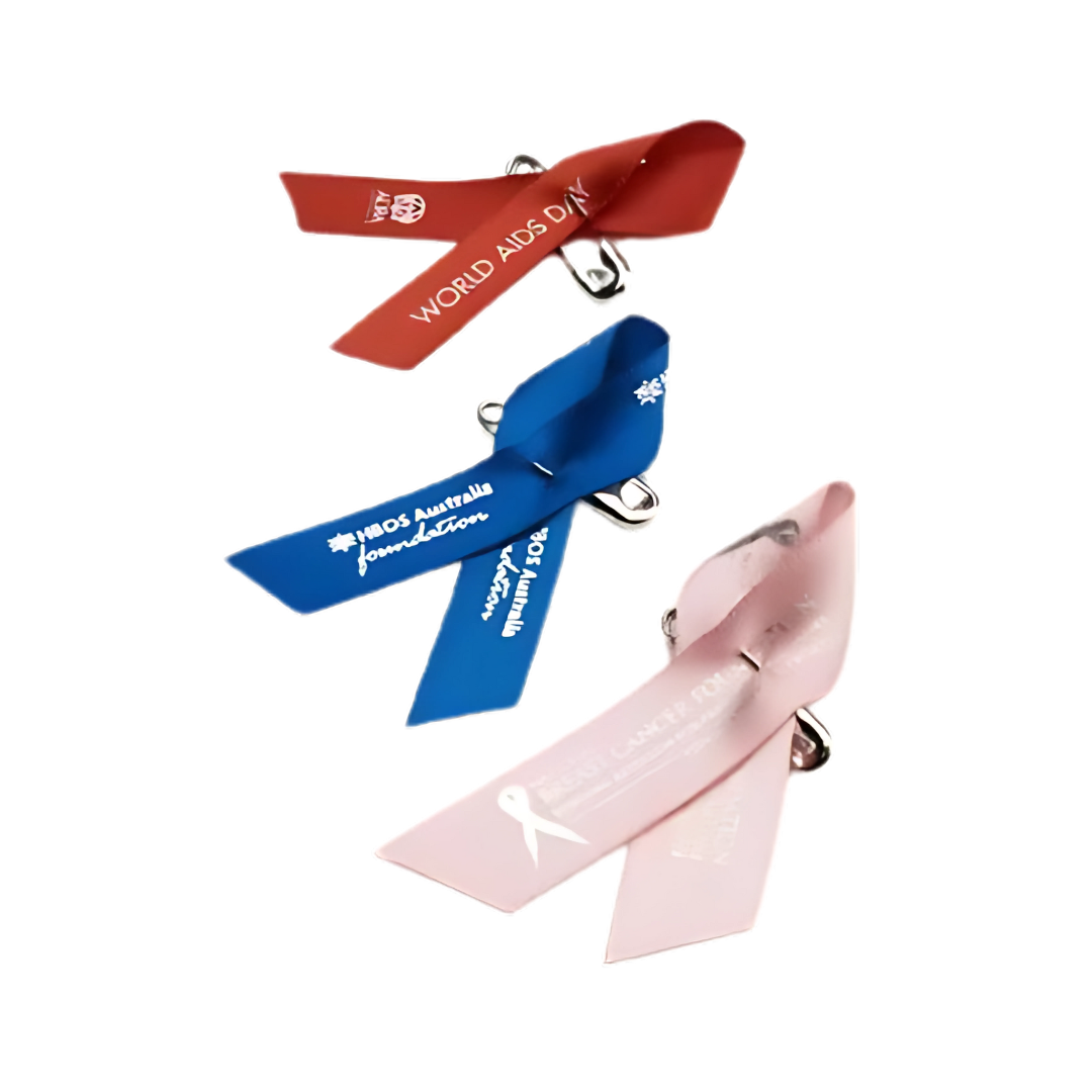 The Promotional Label Pins display three awareness ribbons: red for World AIDS Day, blue for International Day of the Disabled, and pink for Breast Cancer Month, each with relevant text and logos.