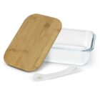A rectangular glass container with a transparent body and a bamboo lid is shown with the lid slightly ajar. A white elastic band is placed in front of the container, suggesting it is used to secure the lid.