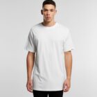In front of a plain white background, a person wears the loose-fitting Plus Tee in white paired with black pants, gazing directly at the camera with a neutral expression.