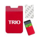 Red silicone card holder with the word TRIO in white letters. It attaches via adhesive backing, shown separately. A smartphone with the holder attached displays green cards inside.