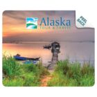 Sunset over a calm lake with boats, dock, and Alaska Tour & Travel logo in the sky.