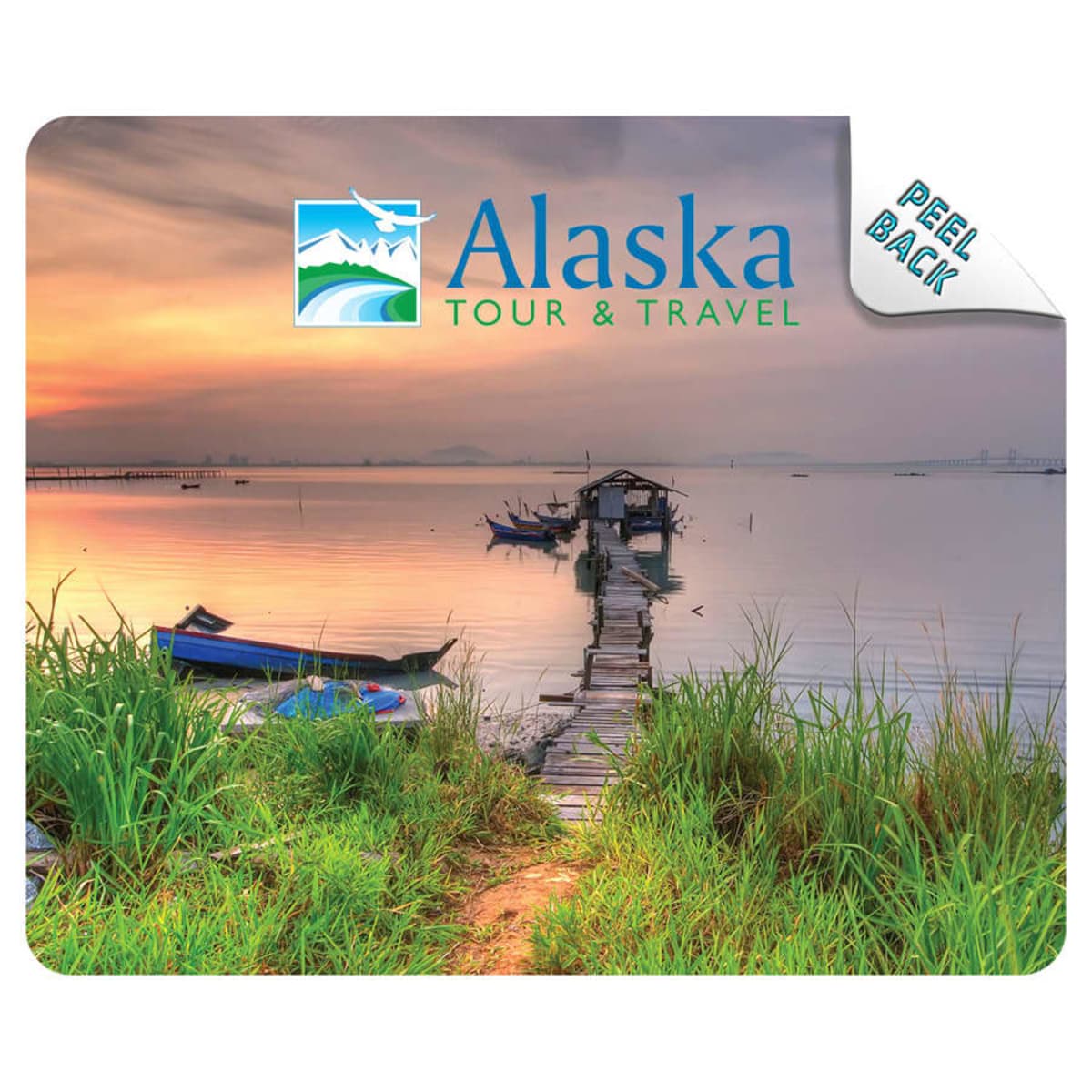 Sunset over a calm lake with boats, dock, and Alaska Tour & Travel logo in the sky.