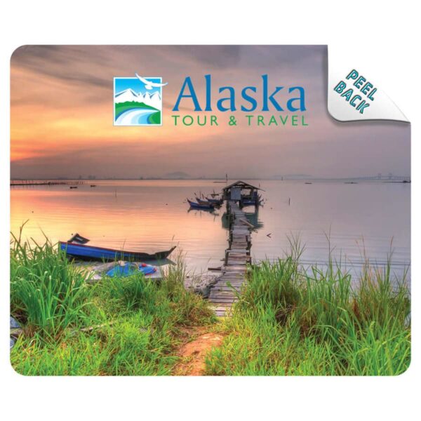 Scenic lake at sunset with boats and a wooden dock, Alaska Tour & Travel logo in corner.