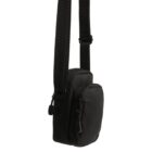 A small, black crossbody bag with adjustable straps and two zippered compartments. The bag is standing upright, showcasing its sleek and minimalist design.